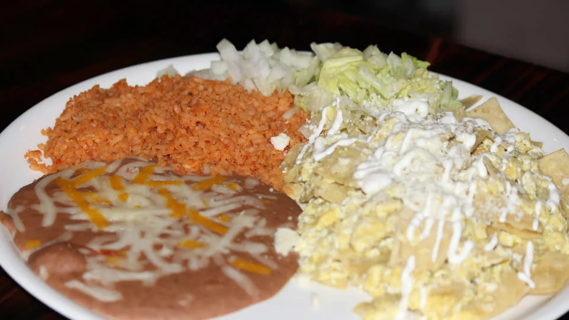 Chilaquiles (Verde or Rojos) - Crispy tortilla chips simmered in your choice of green or red salsa, topped with cheese and crema