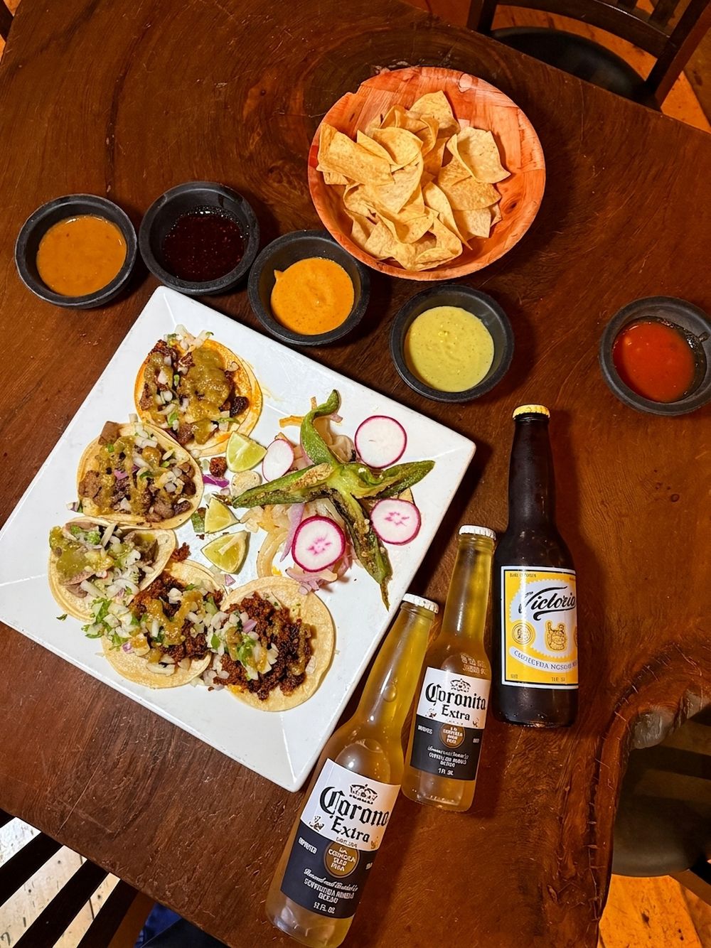 Five street tacos on a square plate at Mi Pueblo in downtown Santa Rosa, with five salsas, chips, grilled jalapeño, radish, lime and three Mexican beers